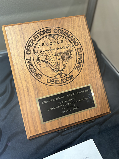Close-up photograph of a plaque presented to Gene Taylor. Please reads: Special Operations Command Europe, USEUCOM, Congressman Gene Taylor, Thanks, Germany, Bosnia, Kosovo, January 2000.