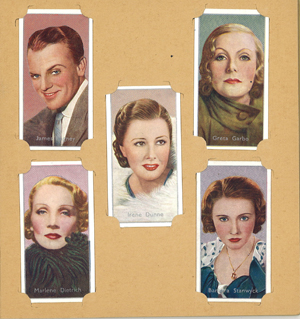 Five cigarette cards of famous film stars from the 1930s including James Cagney, Irene Dunne, Marlene Dietrich, Greta Garbo, and Barbara Stanwyck. The cards are slotted into a page for an album housing cigarette cards. 