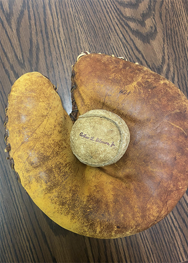Baseball glove with a baseball in the palm of the glove. The ball is inscribed Arthur Lavonne Gilmore, Jr. 